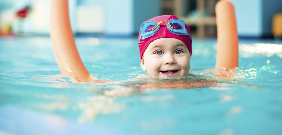 Happy little girl learning to swim with pool noodle